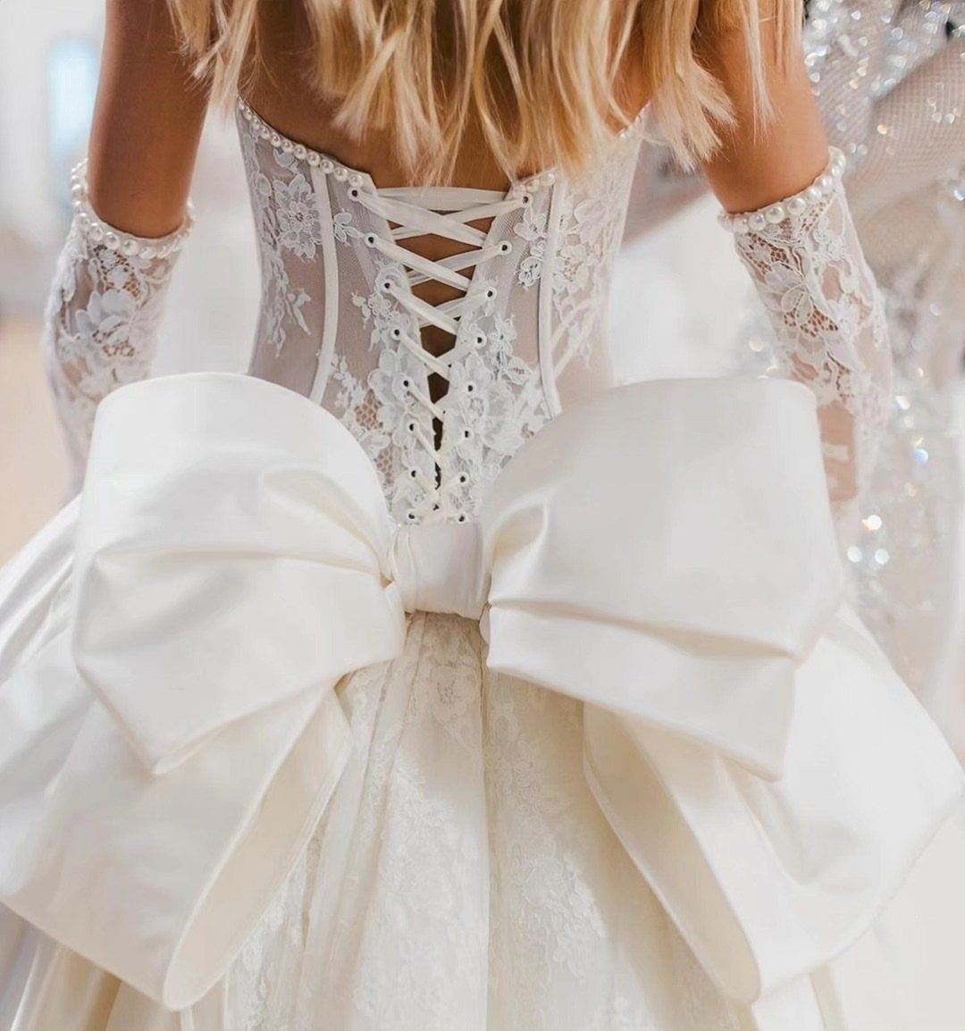 Back of a white lace wedding dress featuring a large statement satin bow.