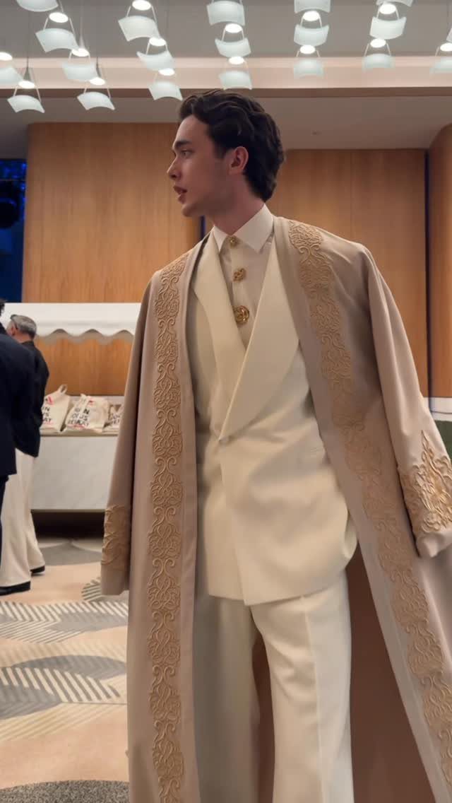 Man in a cream three-piece suit and embroidered beige robe in a modern room