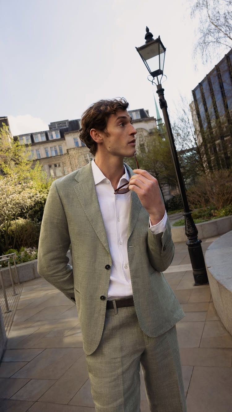 Man in a light sage green linen suit and white shirt outdoors.