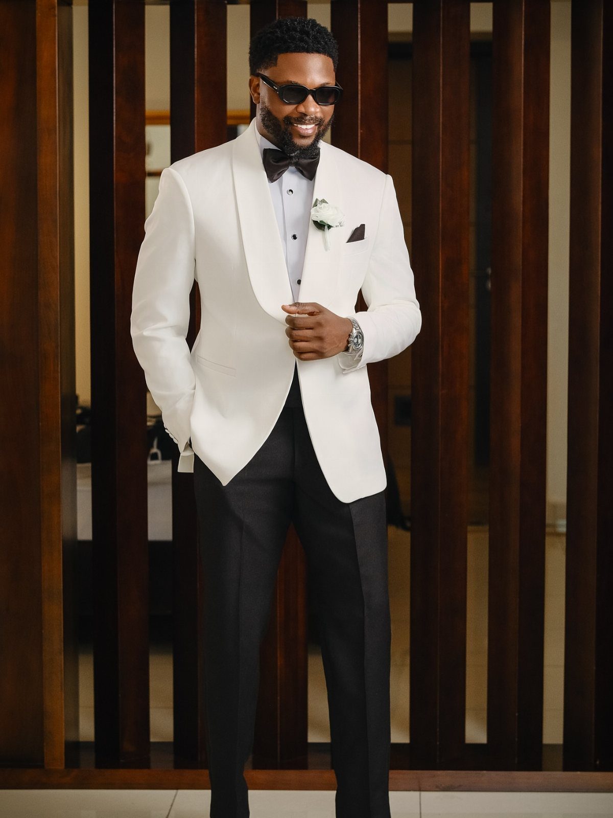 Man in a white tuxedo jacket and black trousers wearing a black bow tie