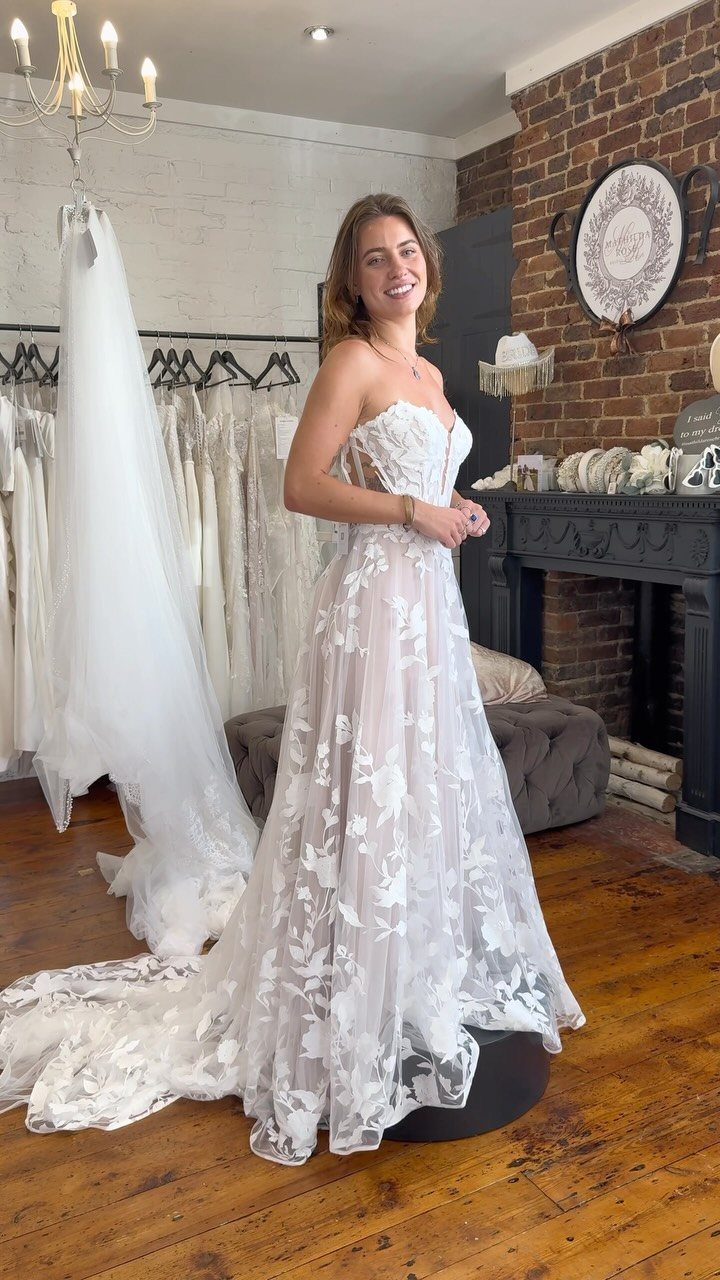 Woman in a white A-line wedding dress with a sweetheart neckline and floral lace.