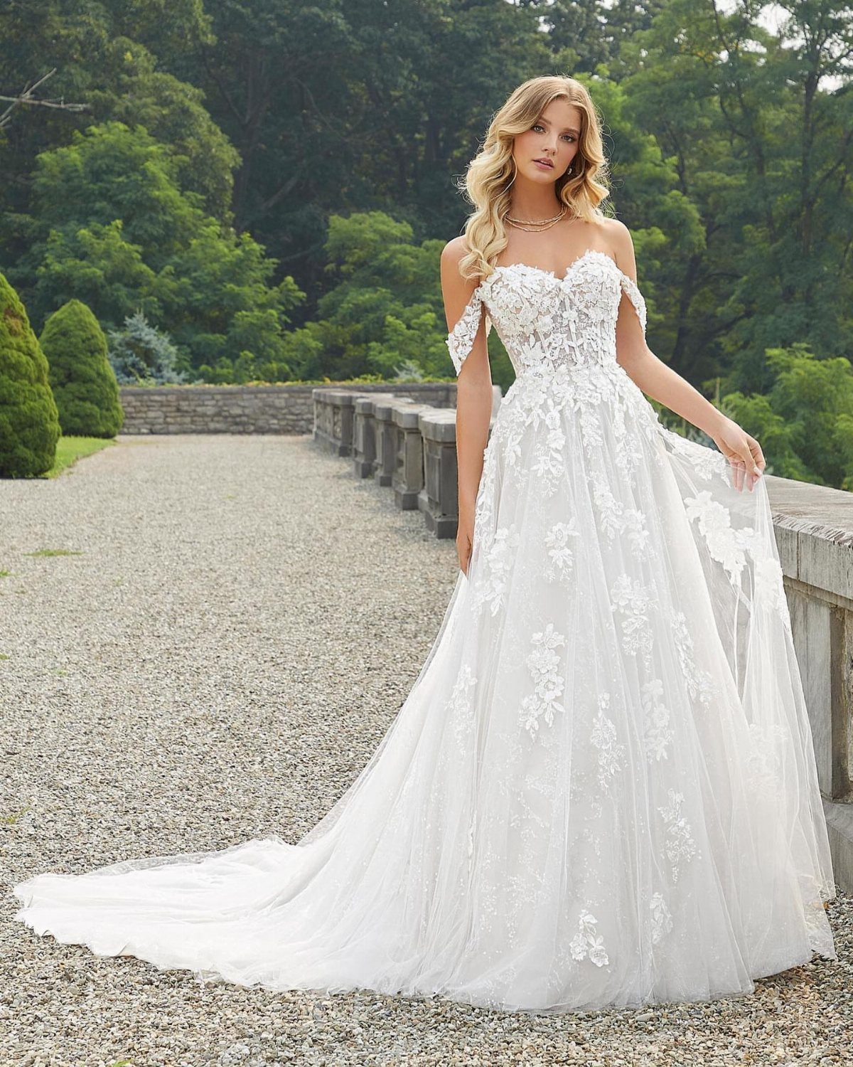 Woman in a white lace wedding dress with a sweetheart neckline and off-shoulder straps.