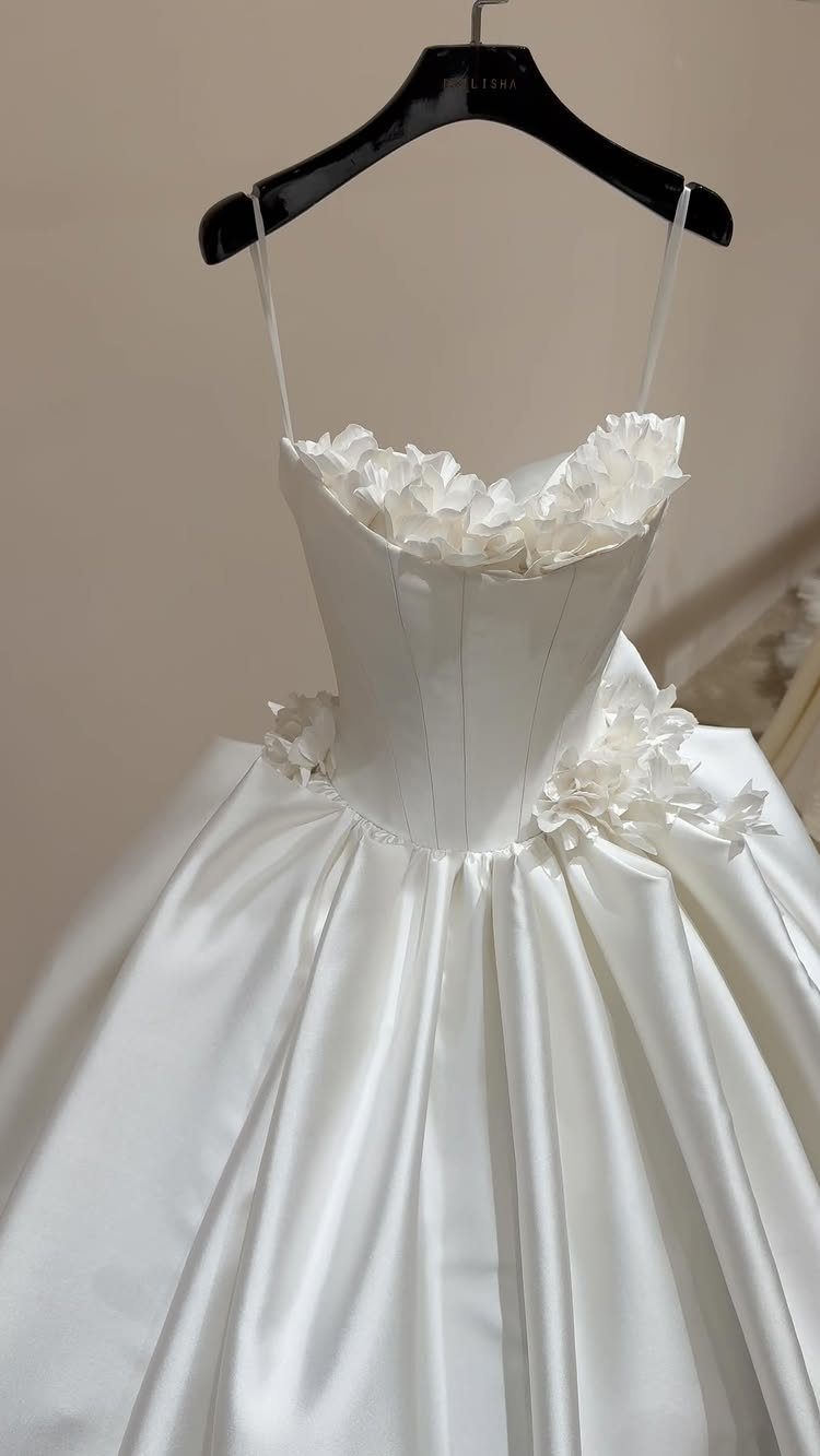 White satin wedding dress with ruffled sweetheart neckline hanging on a black hanger