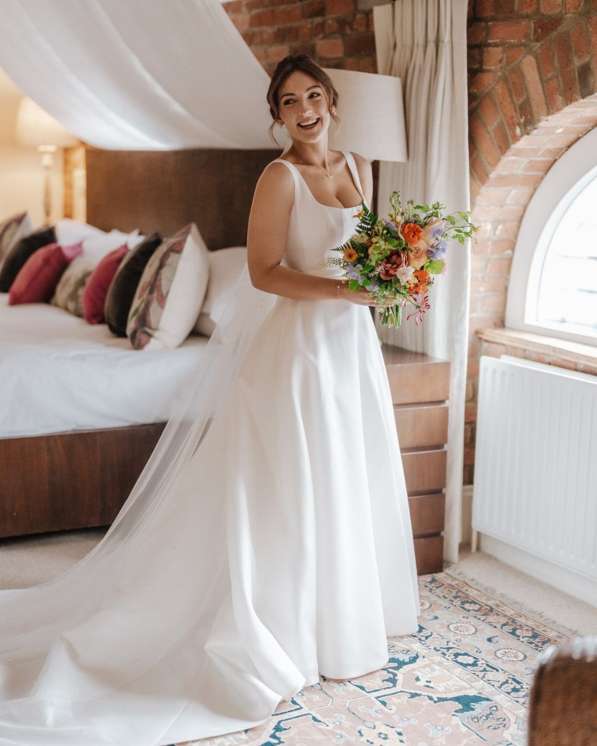 Woman in a white sweetheart neckline wedding dress holding a colorful floral bouquet.