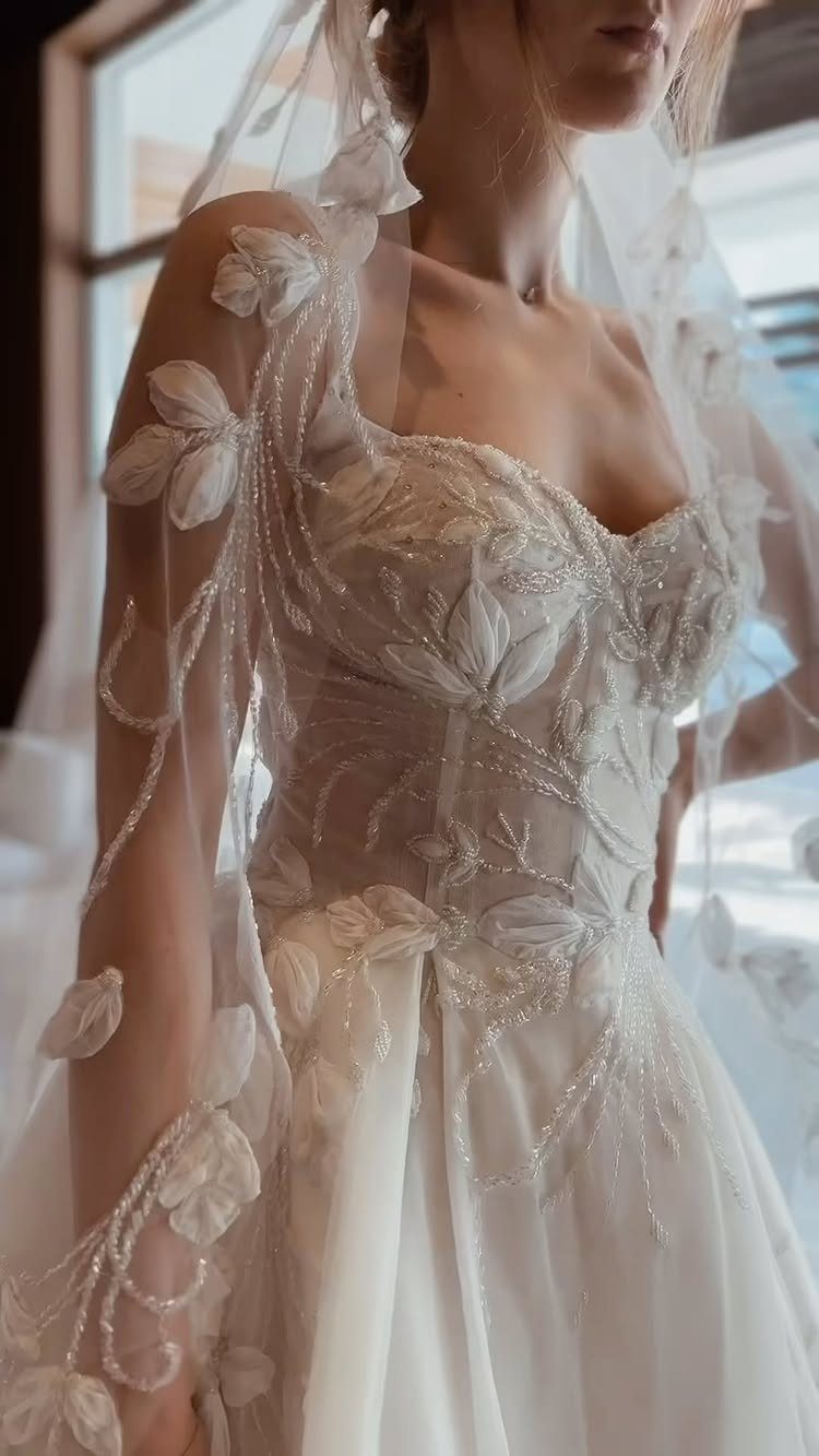 Woman in a beaded white wedding dress with a sweetheart neckline and floral veil