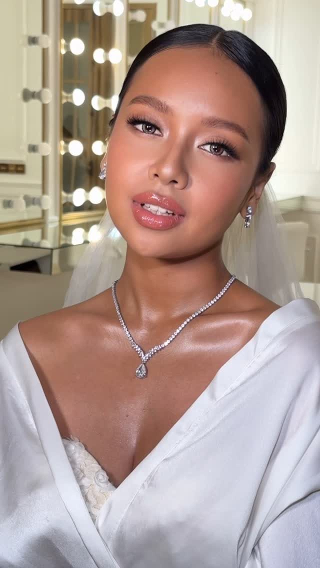 Woman with tan skin wearing bridal makeup, a white veil, and diamond necklace.