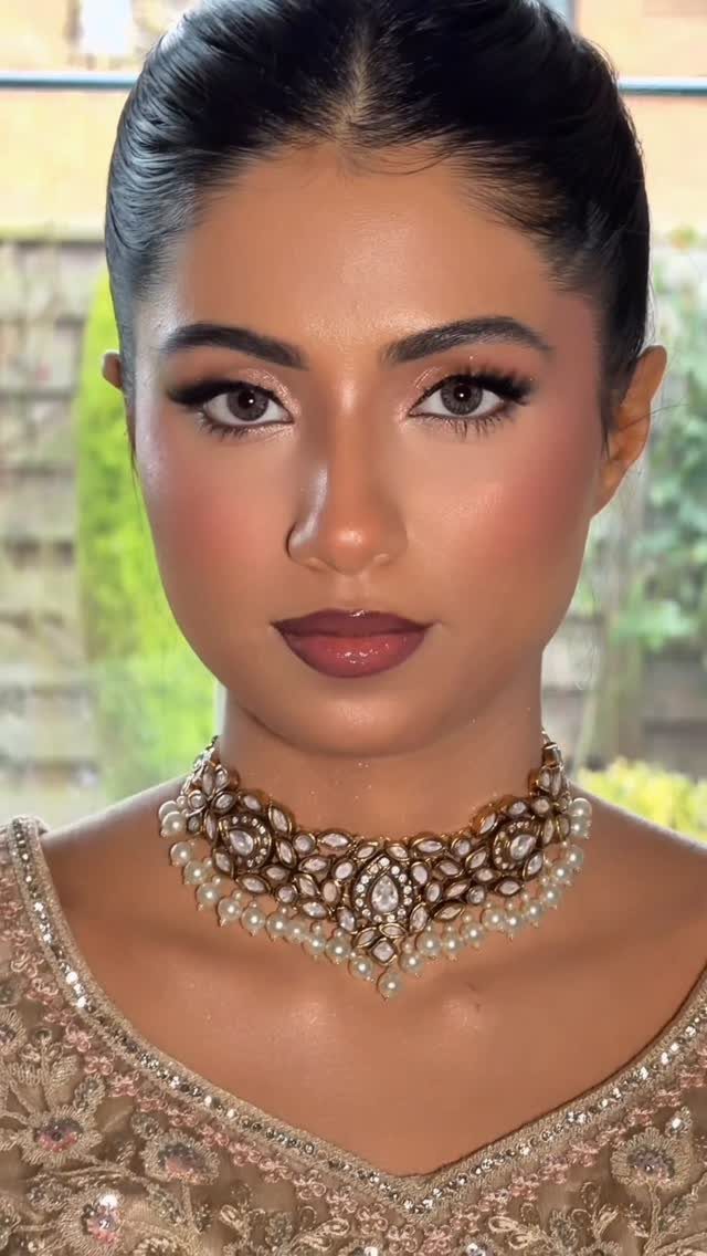 Woman with tan skin wearing glamorous wedding makeup and an ornate pearl choker necklace