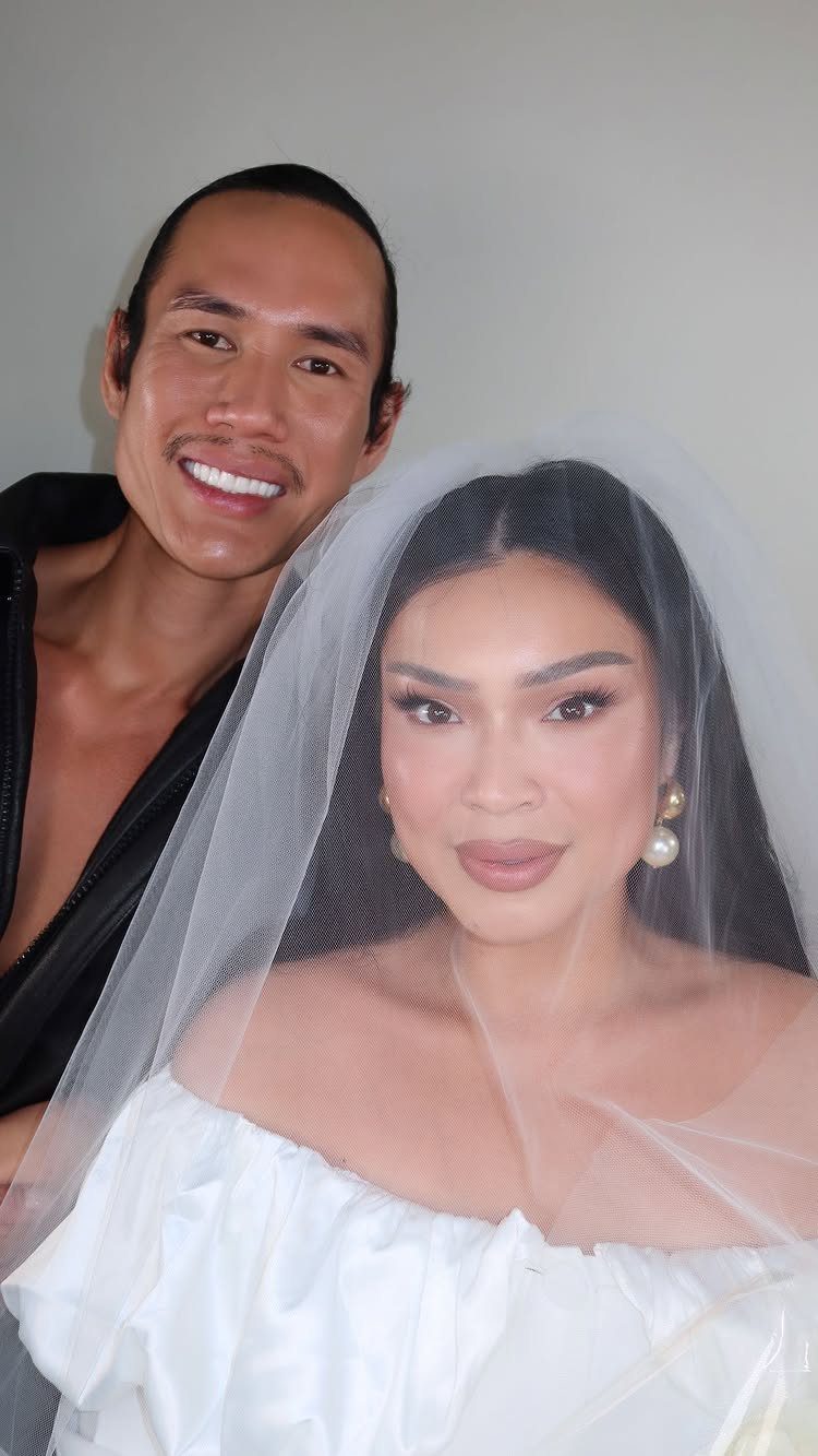 Bride with matte makeup and a white veil posing with her groom.