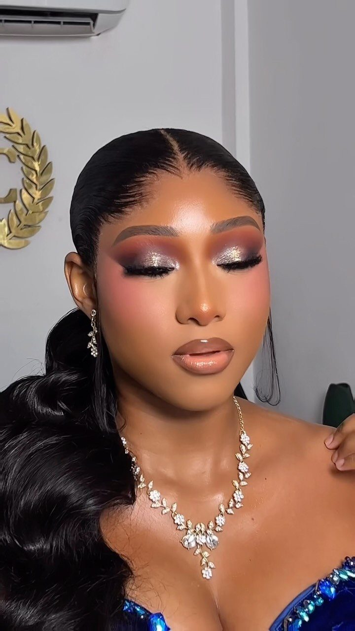 Woman with dramatic smokey eye makeup, gold shimmer, and a diamond necklace.