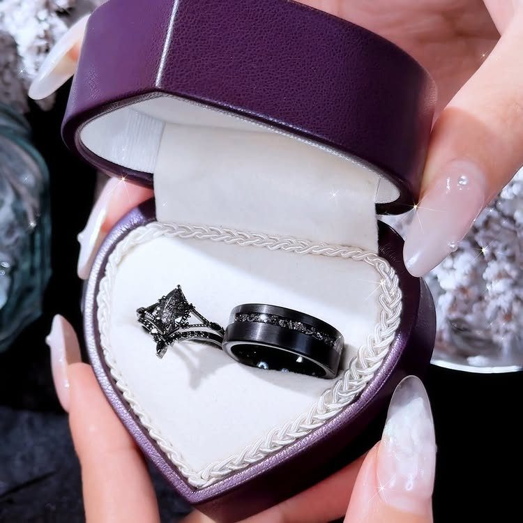 Black diamond engagement ring and matching band in a purple heart-shaped box.