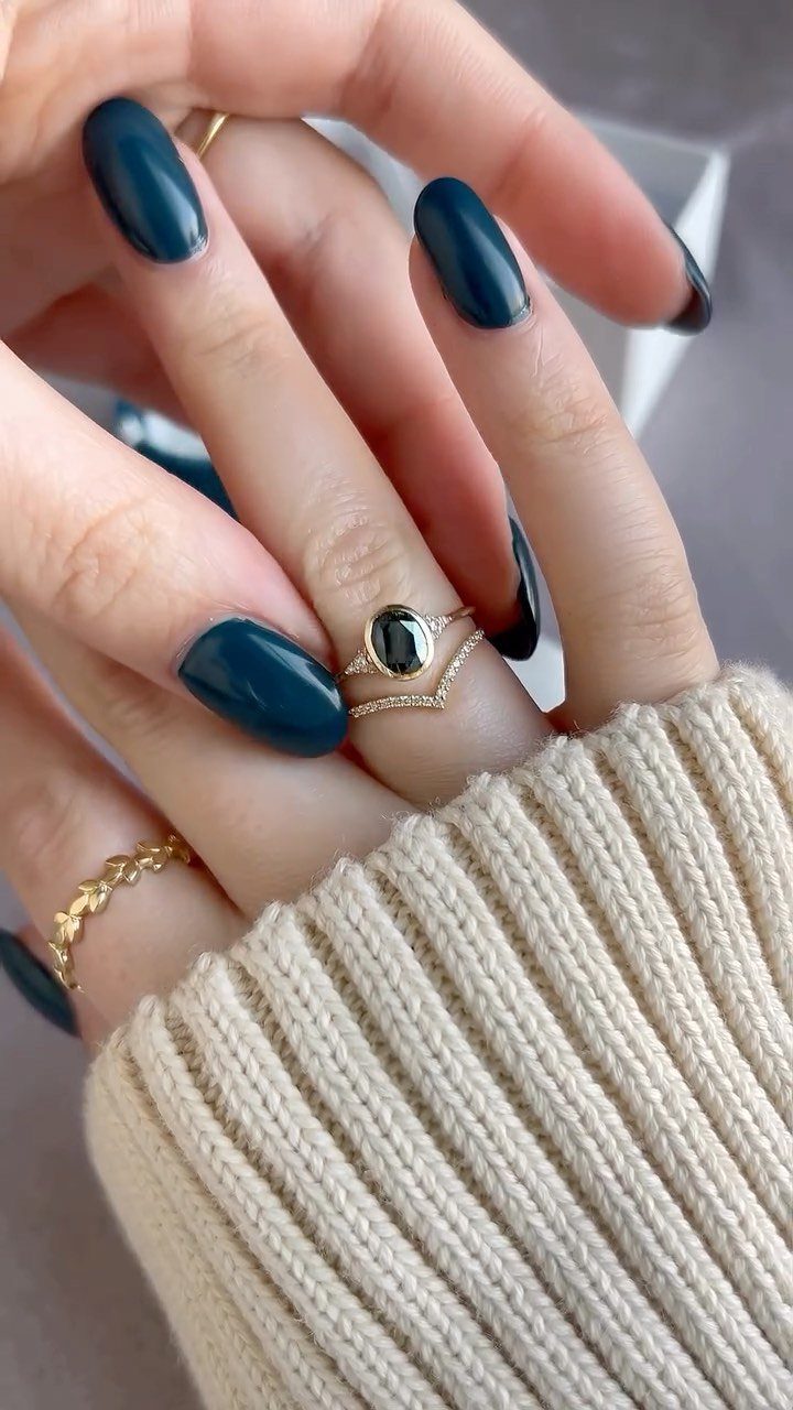 Gold sapphire engagement ring and diamond band on a hand with teal nails