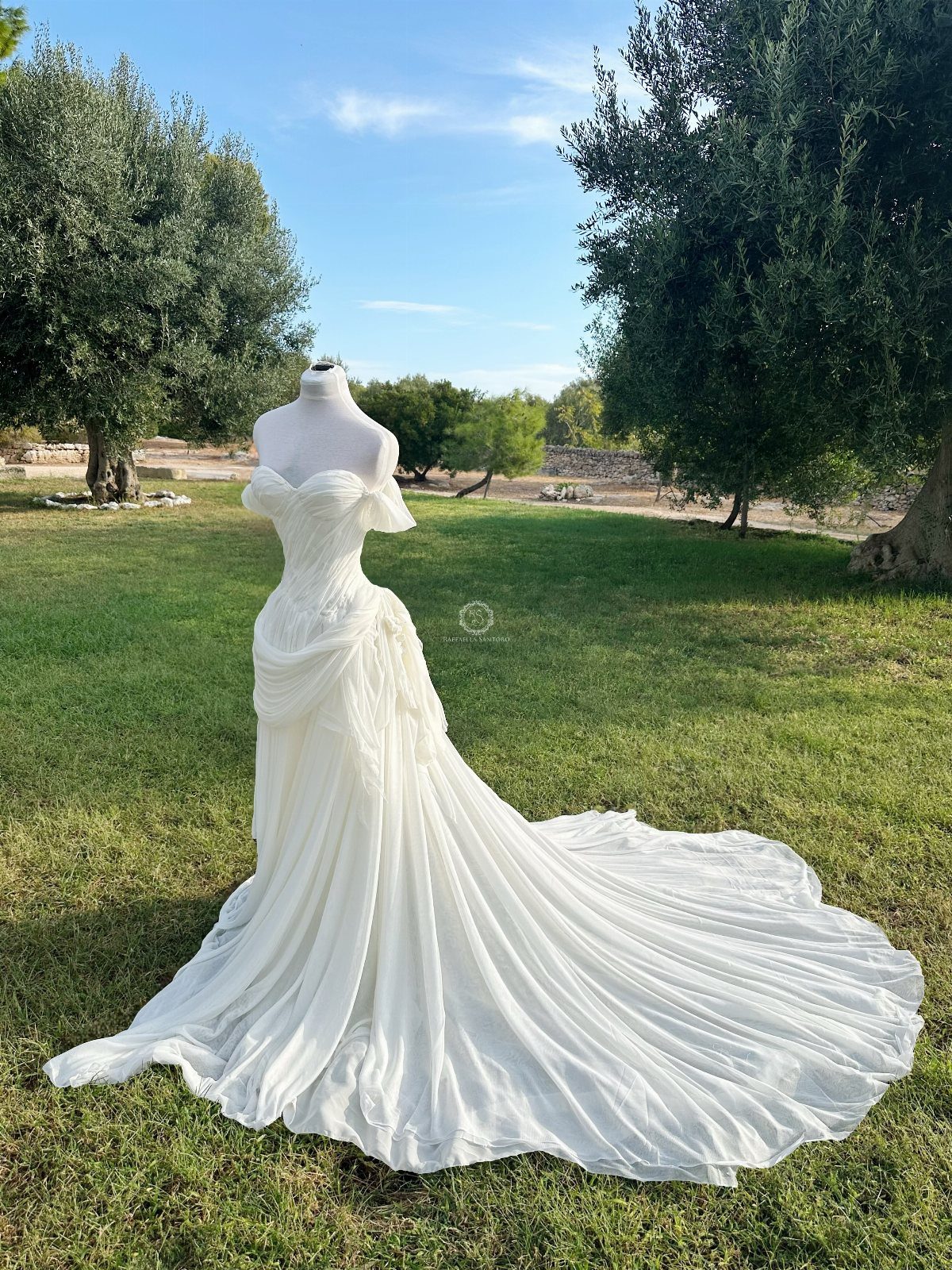 White wedding dress on a mannequin with draped fabric in a grassy field
