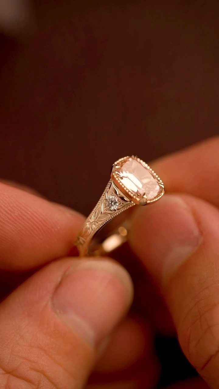 Rose gold vintage ring with cushion-cut diamond and milgrain bezel setting held by fingers