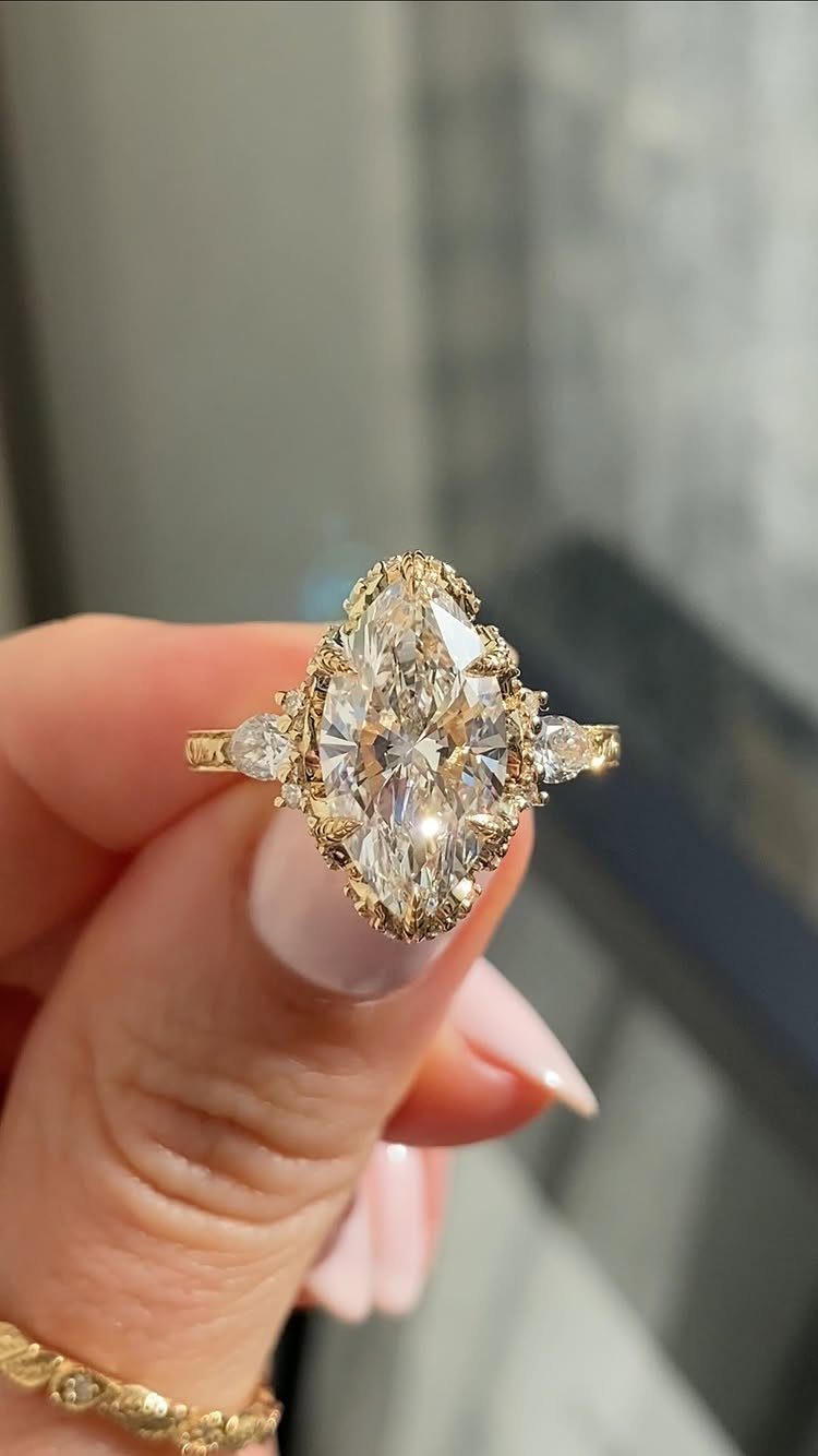 Gold vintage style ring with a marquise diamond held by a hand