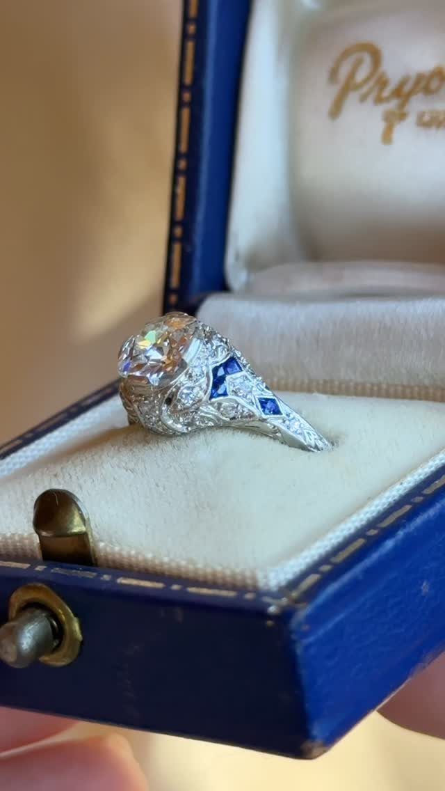 Silver ring with large diamond and blue sapphires in a blue velvet box