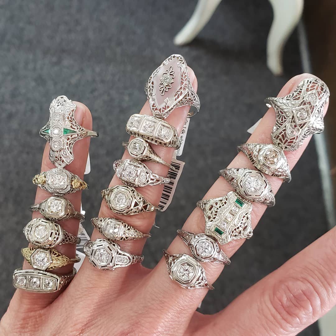 Ornate vintage rings with filigree and diamonds worn on three fingers of a hand.