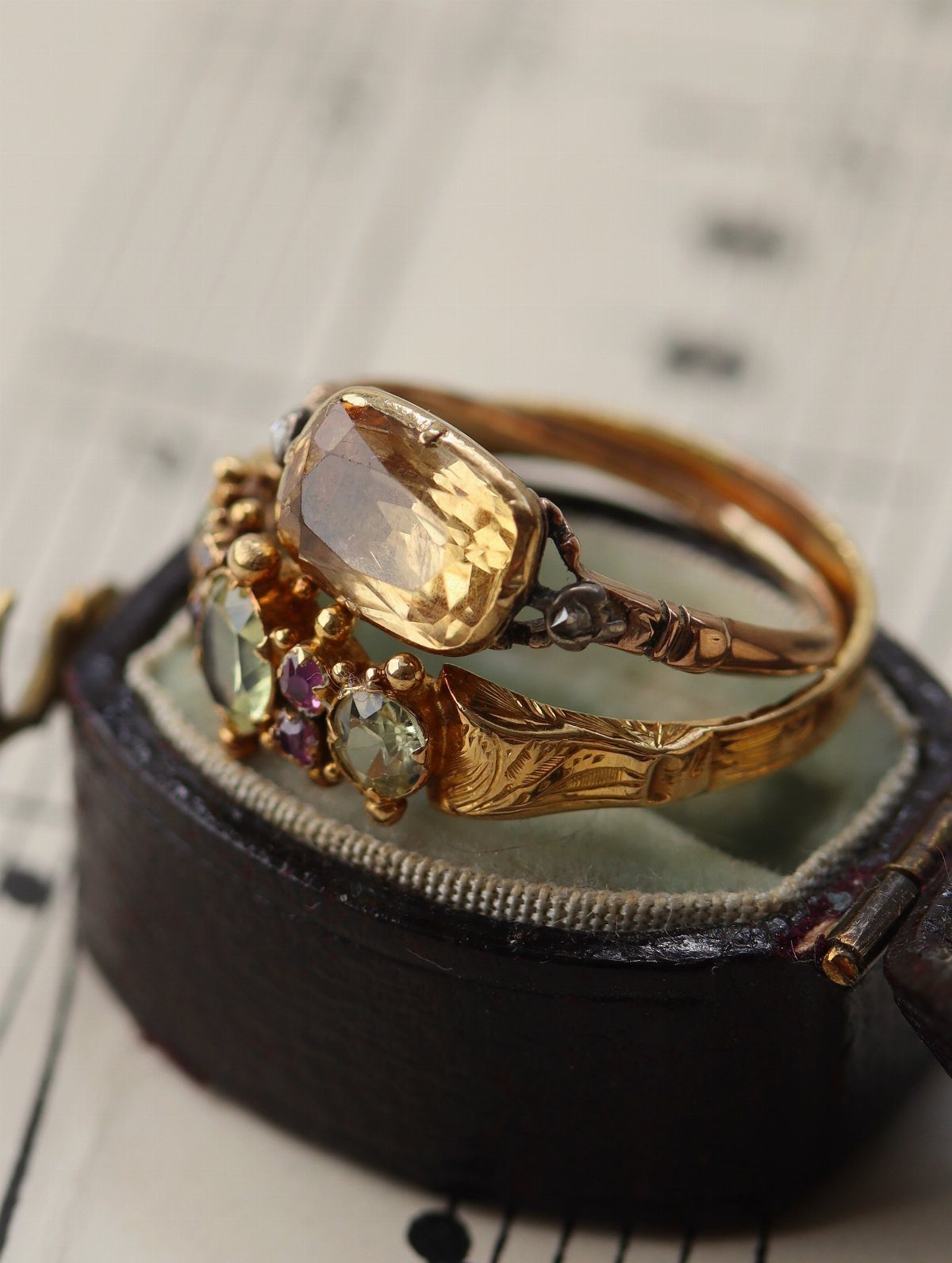 Two ornate gold vintage rings with gemstones resting on a black velvet box.