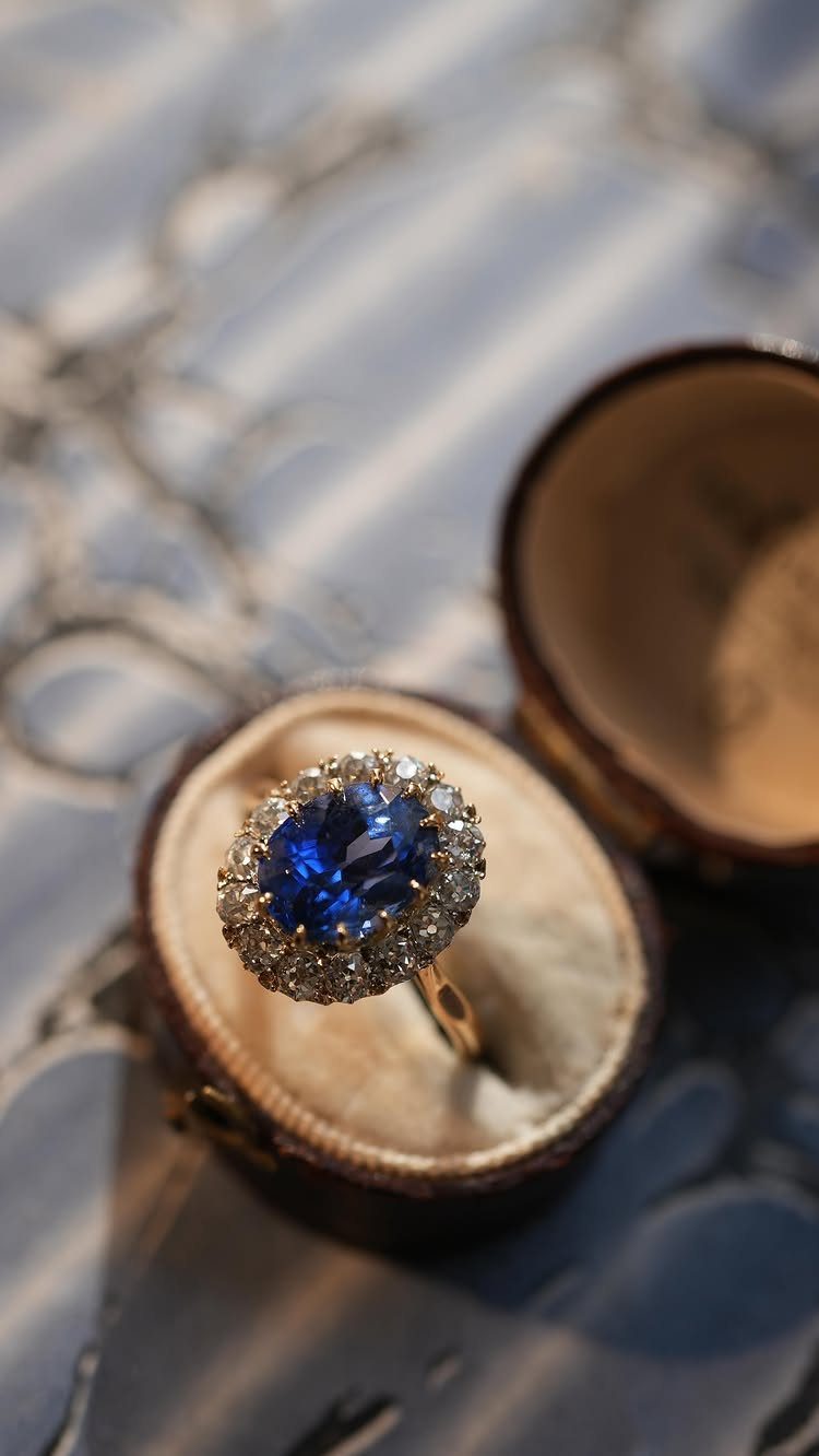 Blue sapphire and diamond cluster ring resting in a vintage velvet jewelry box.