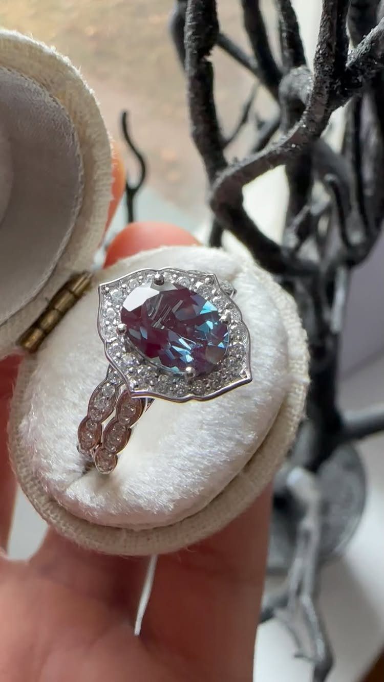 Iridescent blue-purple gemstone ring with diamond halo in a white velvet box