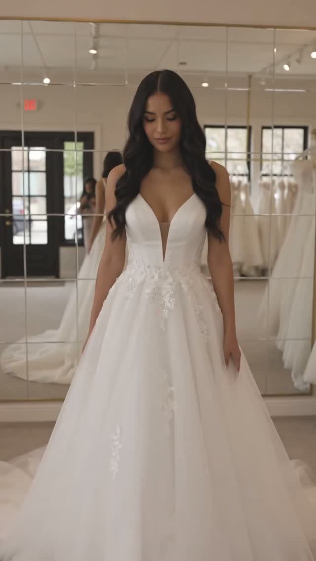 Woman wearing a white A-line wedding dress with a deep V-neckline in a boutique.