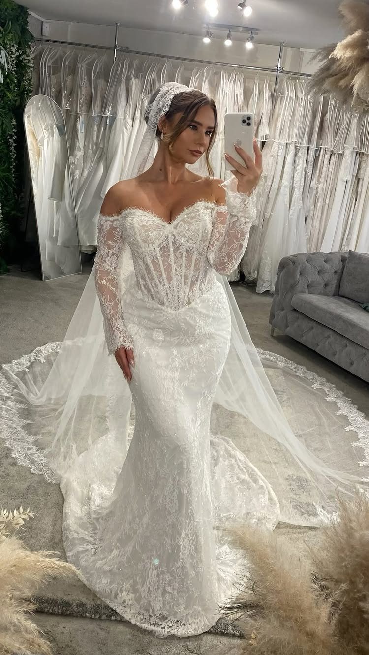 Woman in a white lace mermaid wedding dress with an off-the-shoulder neckline.