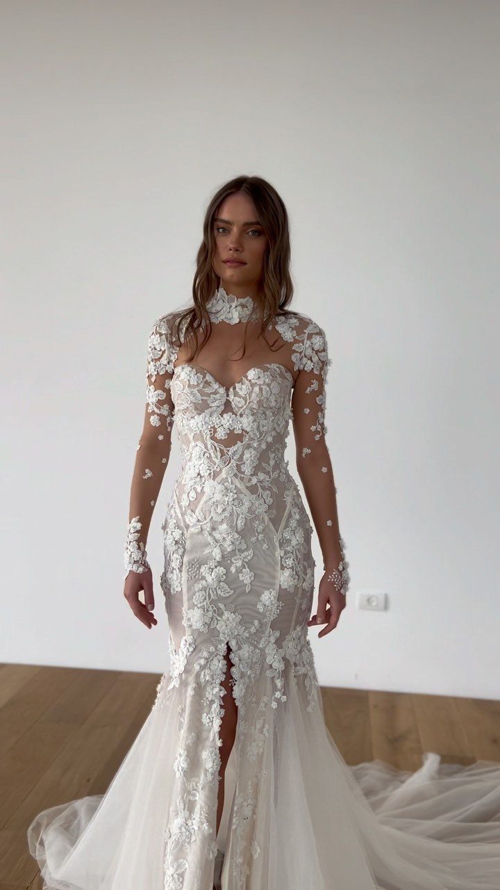 Woman in a white lace trumpet wedding gown with long sheer sleeves.