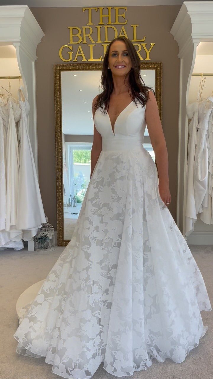Woman in a white V-neck wedding dress with a floral lace skirt.