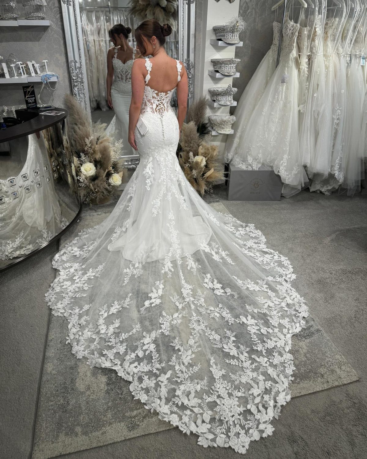 Woman wearing a white lace fit-and-flare wedding gown with a long floral train