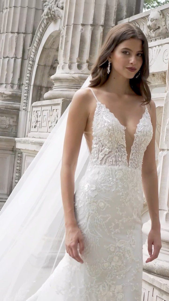 Woman in a white lace sheath wedding dress with a deep V-neckline and veil.