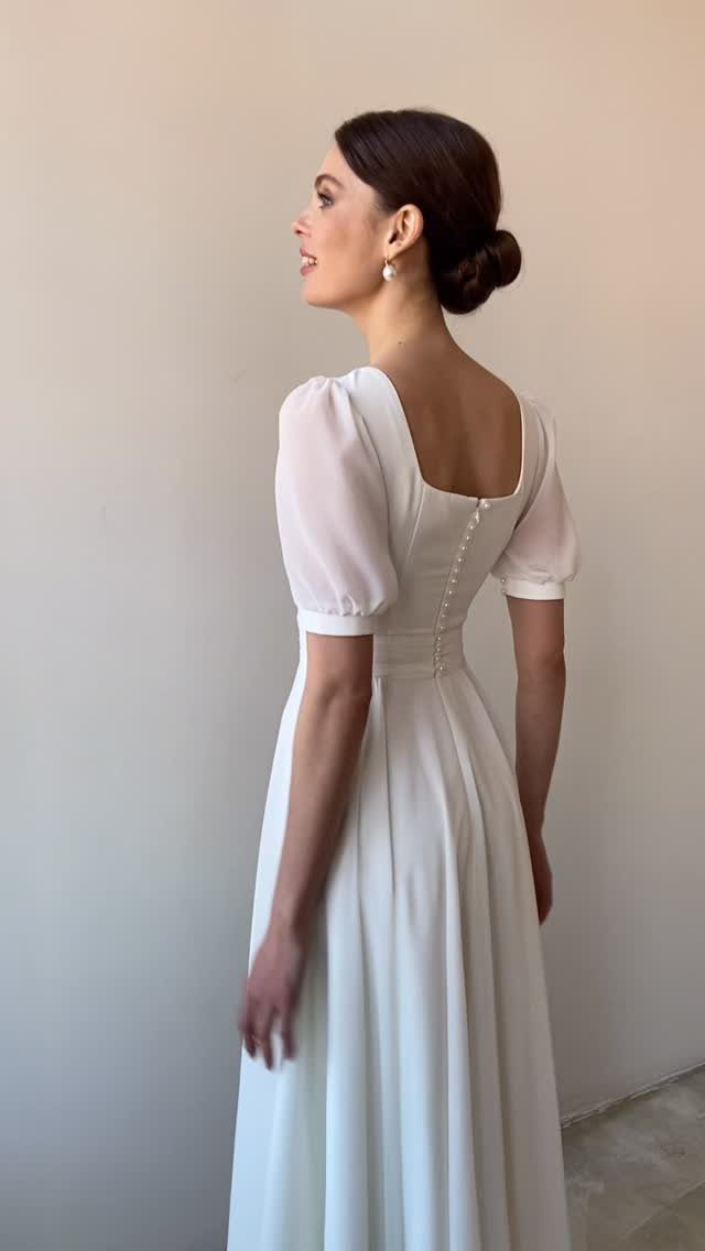 Woman in a white A-line wedding dress with short sleeves and button back.