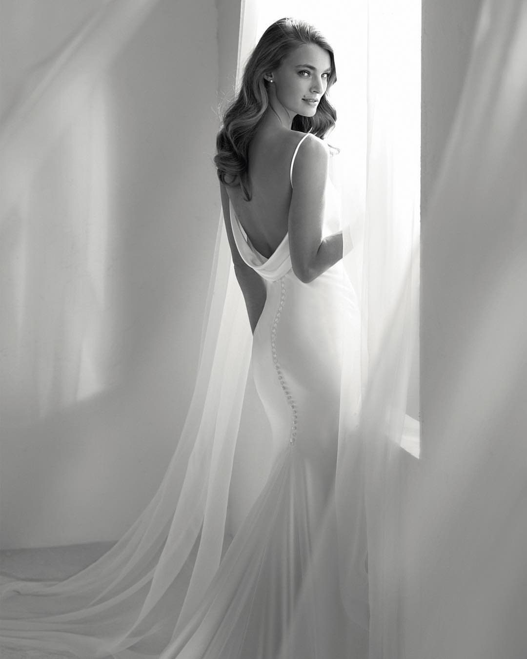 Woman in a sleek white satin wedding gown with a low back and buttons.