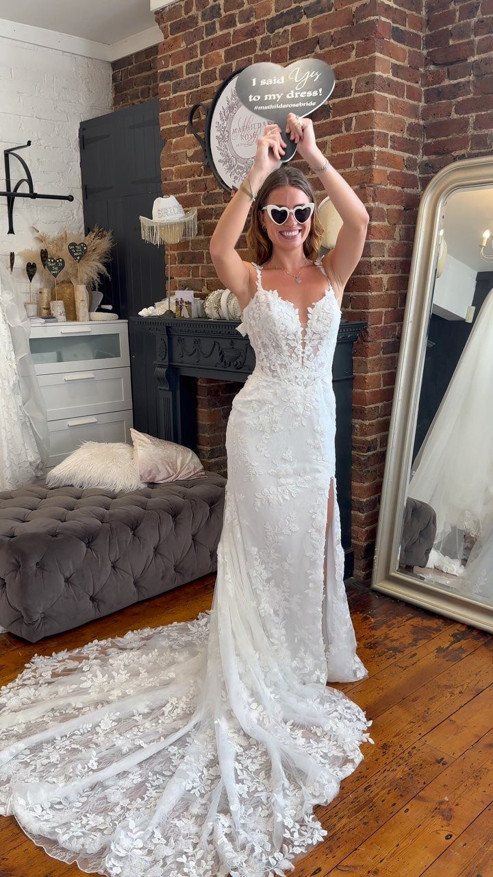 Woman in a white lace V-neck wedding dress with a long train.