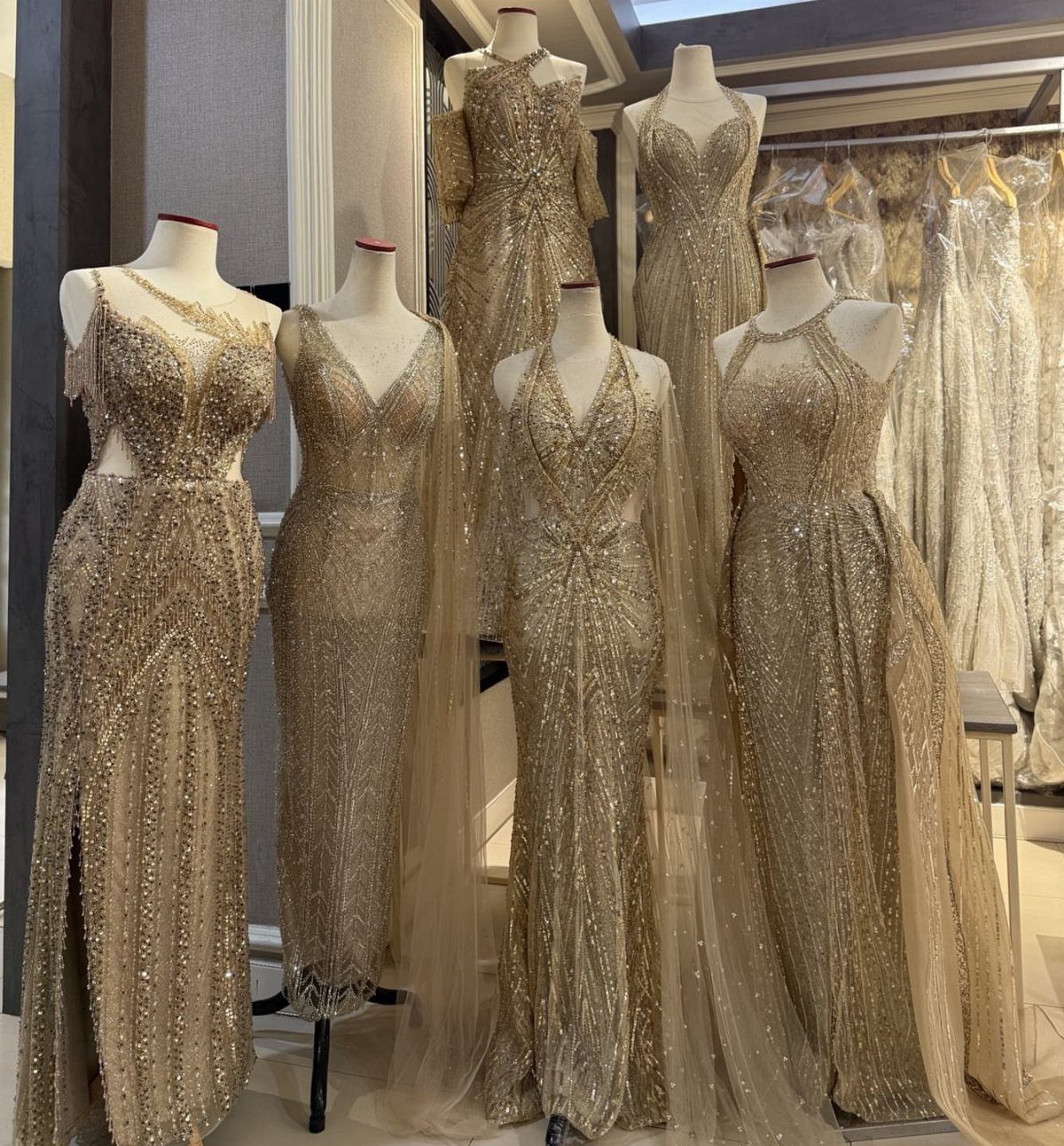 Gold metallic sequined wedding gowns displayed on mannequins in a bridal boutique.
