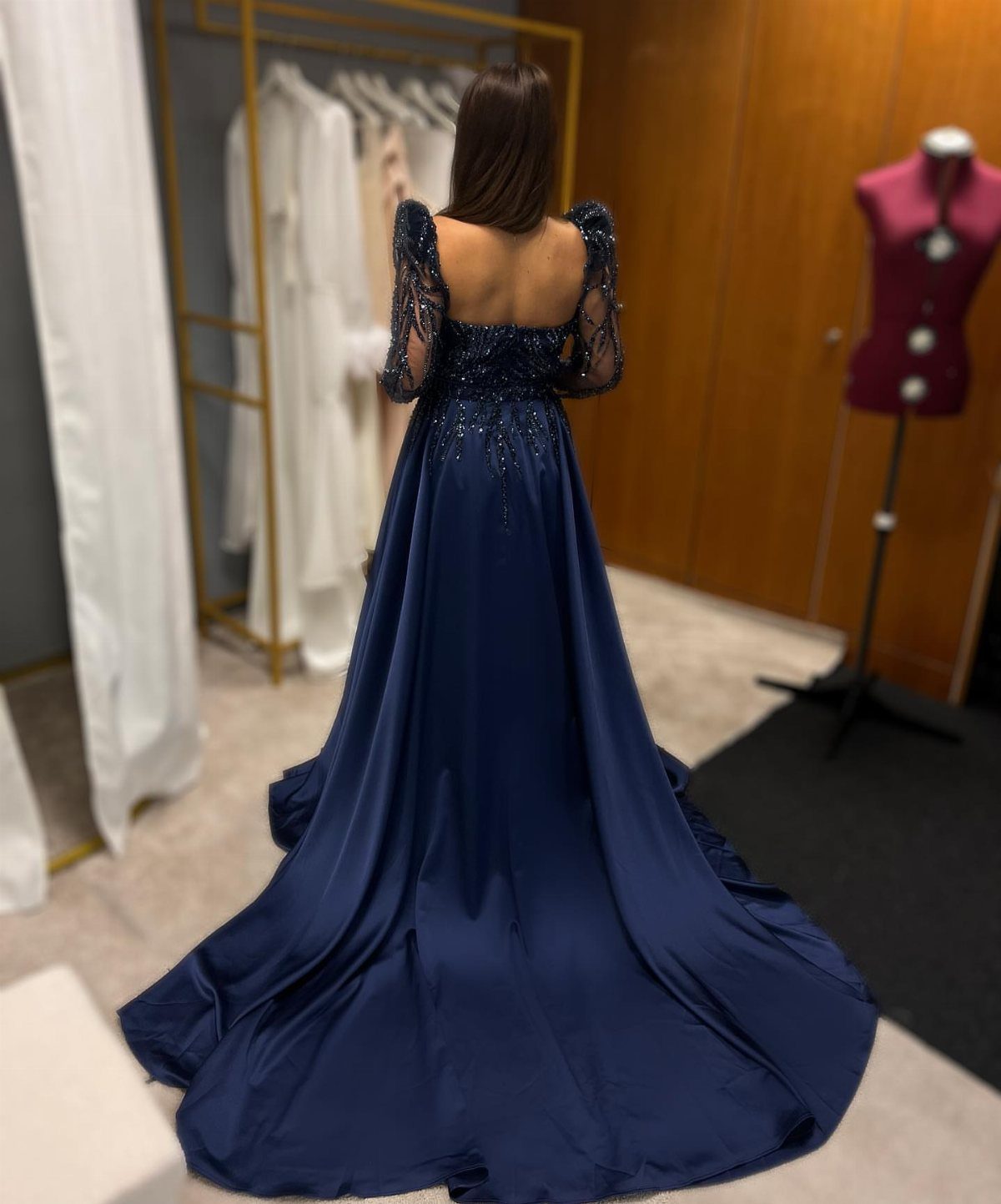 Woman wearing a navy blue satin wedding dress with a long train and beading.