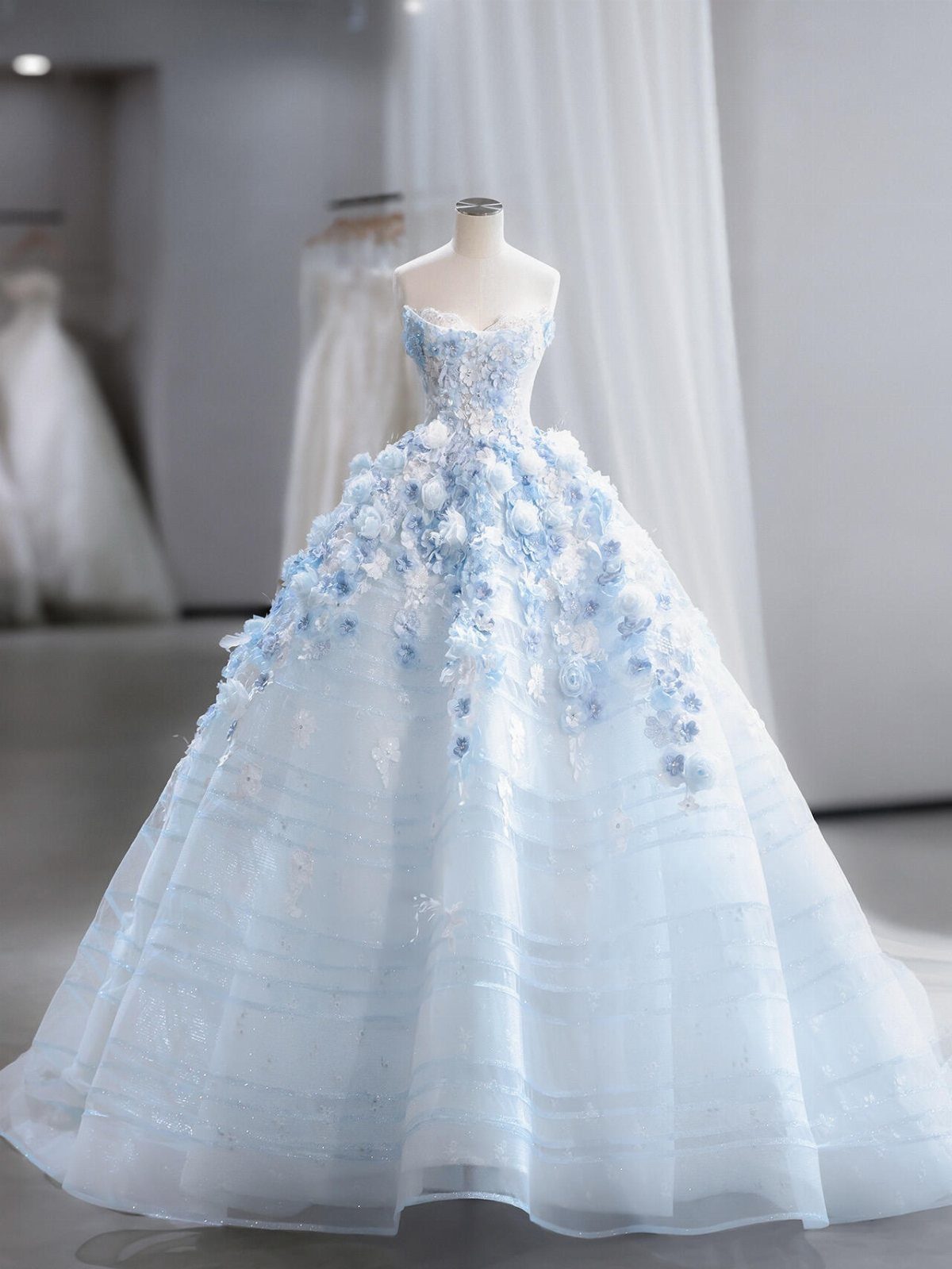 Light blue ballgown wedding dress with 3D floral appliqués on a mannequin
