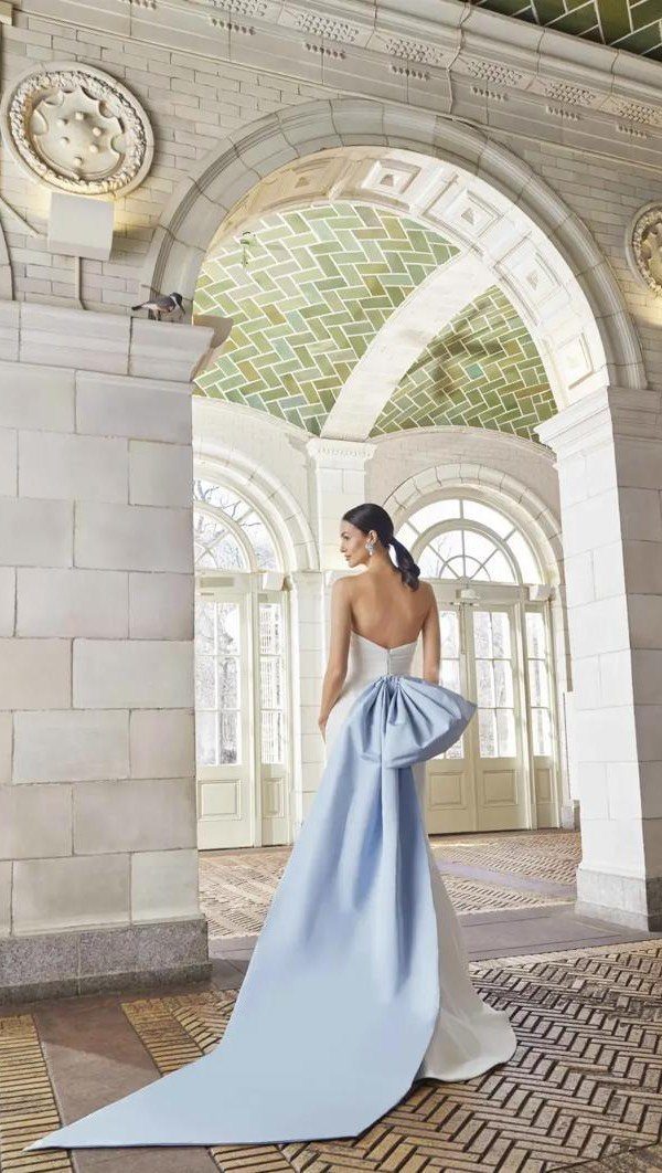 Woman in a white wedding dress with a large light blue satin bow train.