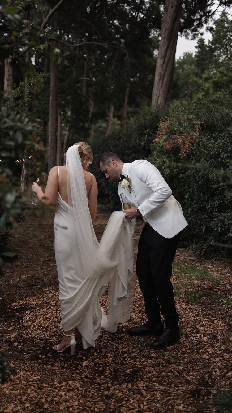 Bride in a sleek white wedding dress and groom in a white tuxedo jacket.