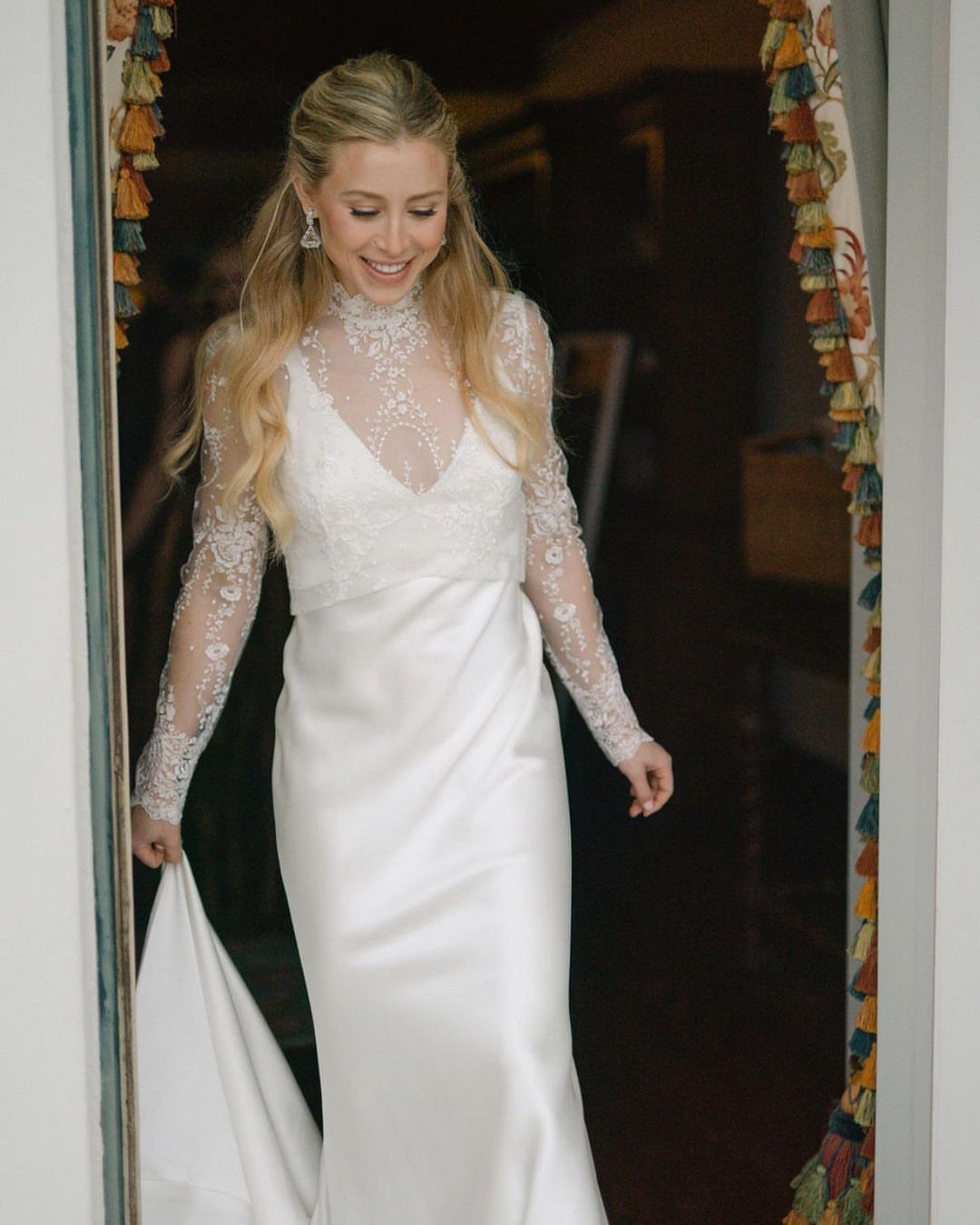 Woman wearing a white wedding dress with lace sleeves and satin skirt.