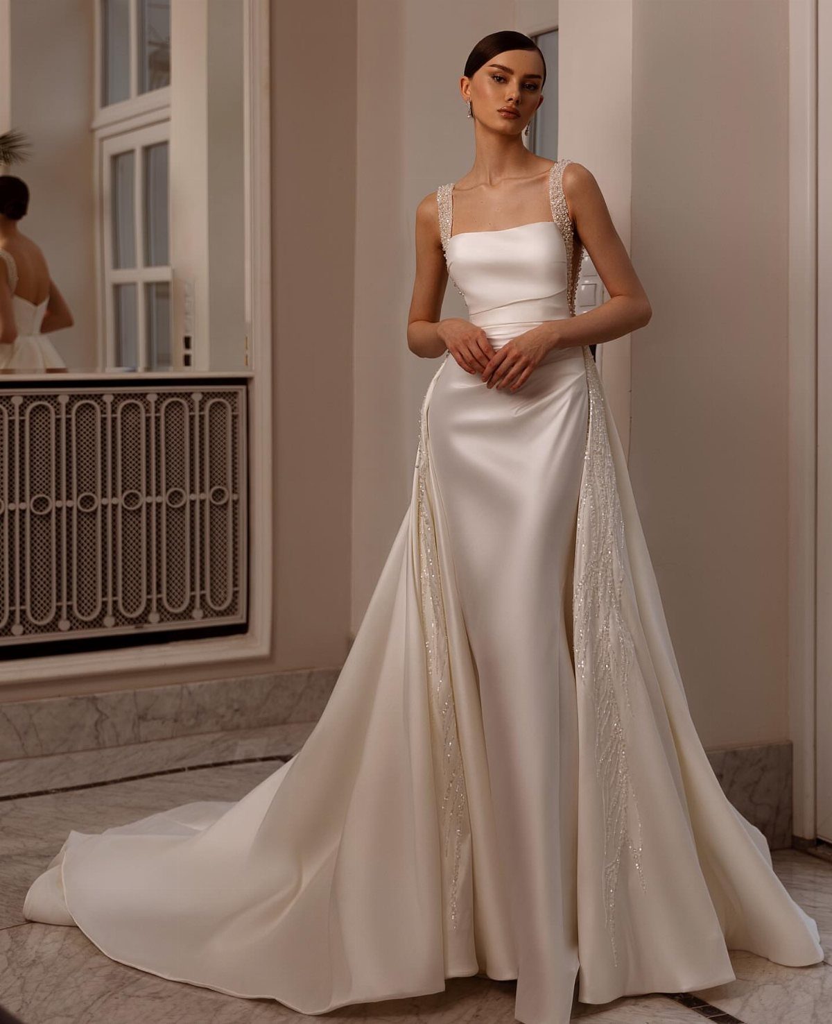 Woman in a sleek white satin wedding gown with a detachable overskirt.