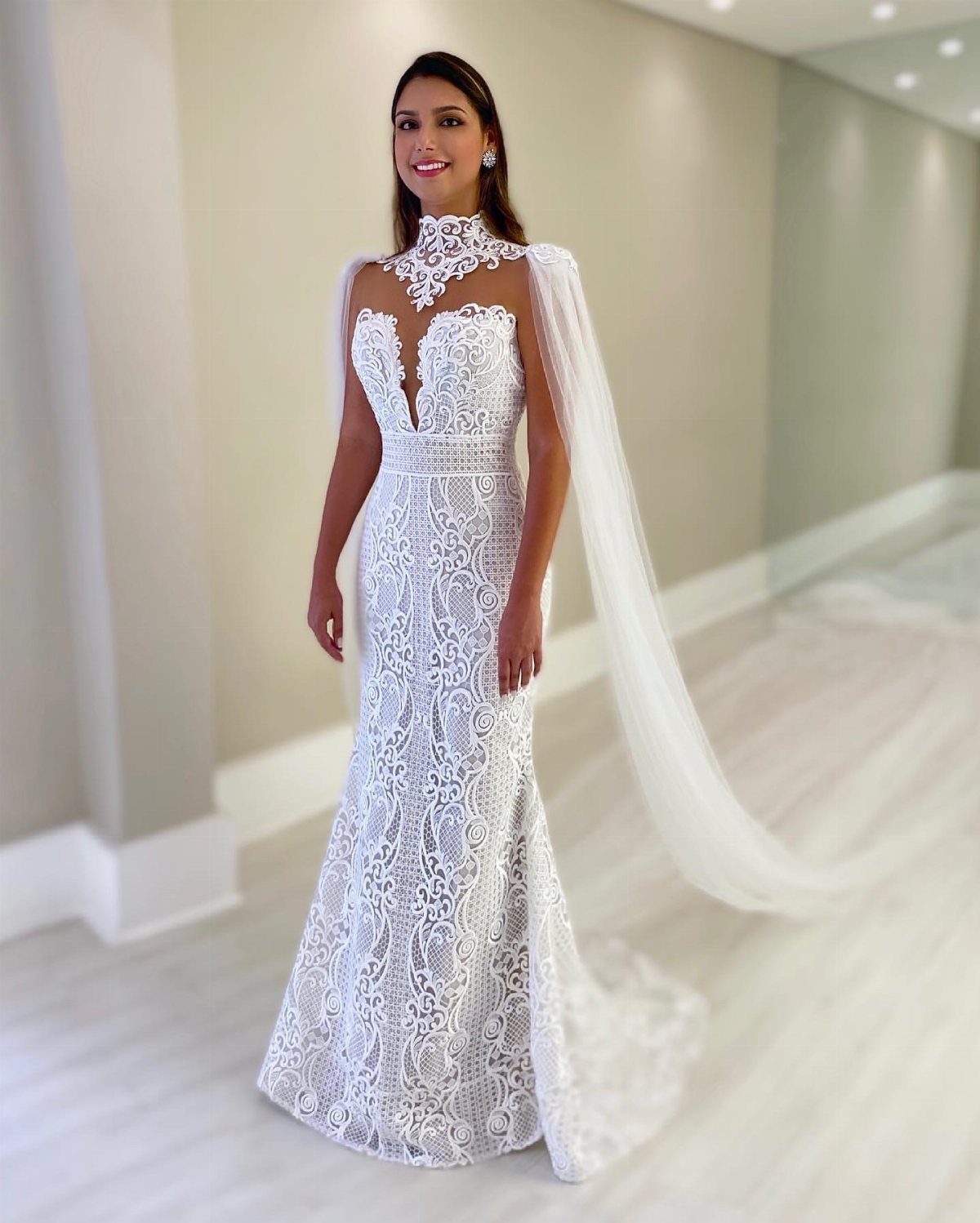 Woman in a white lace wedding dress with a high neck and sheer cape.