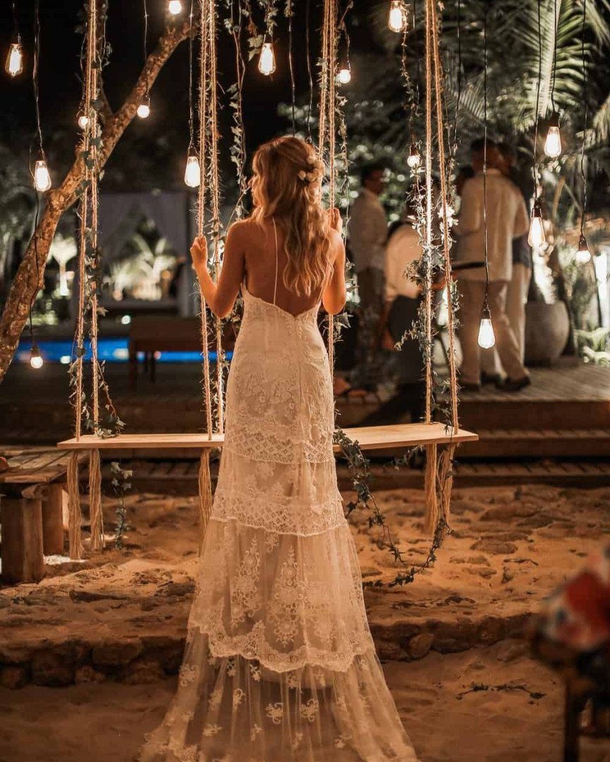 Woman in a white lace wedding dress standing in a lit outdoor garden
