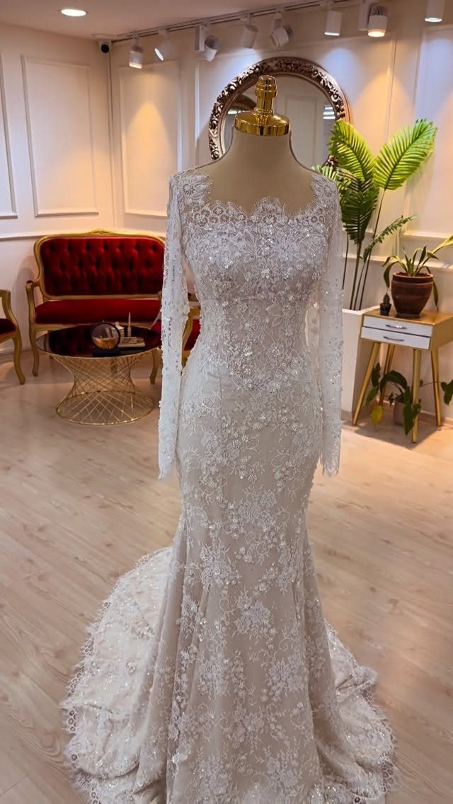 White lace wedding dress with long sleeves on a mannequin in a boutique.
