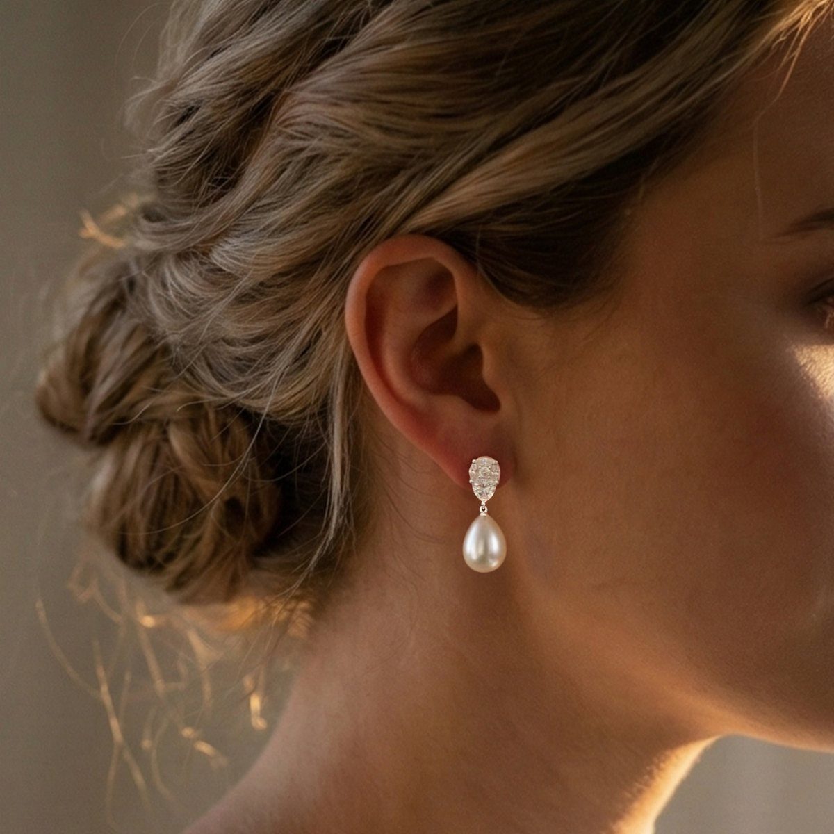 Woman with braided updo wearing a teardrop pearl and diamond earring.
