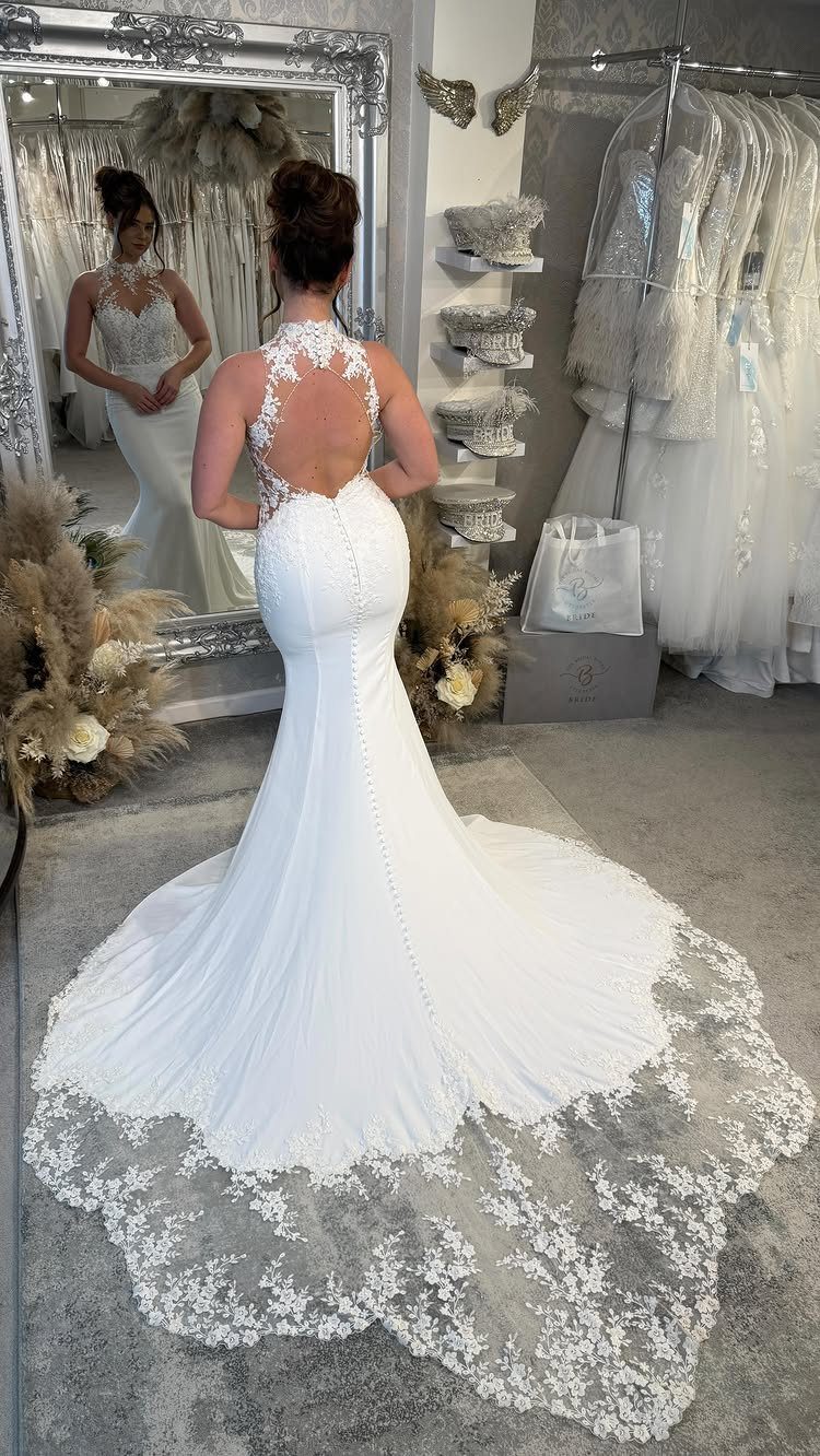 Woman in a white fit-and-flare wedding dress with a lace back and train.