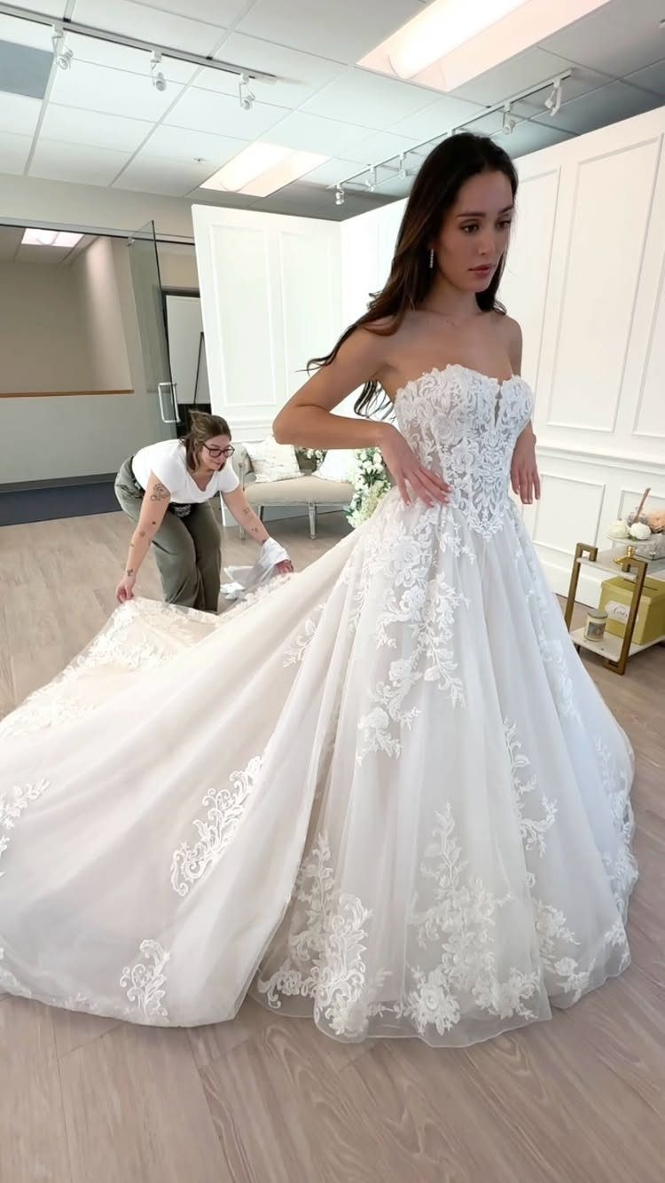 Woman in a white strapless A-line wedding dress with lace floral embroidery.
