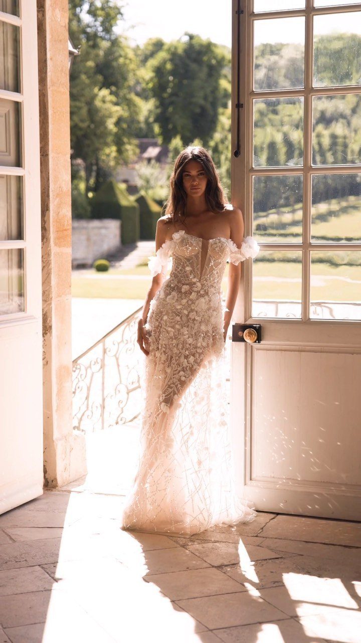 Woman in a white floral mermaid wedding dress standing in a sunny doorway