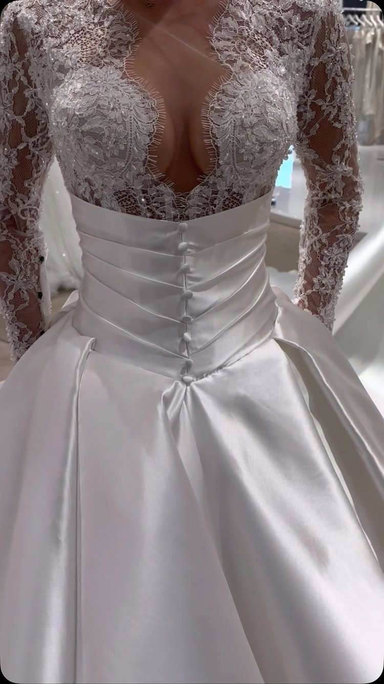 White wedding dress with a deep plunging neckline and lace long sleeves.