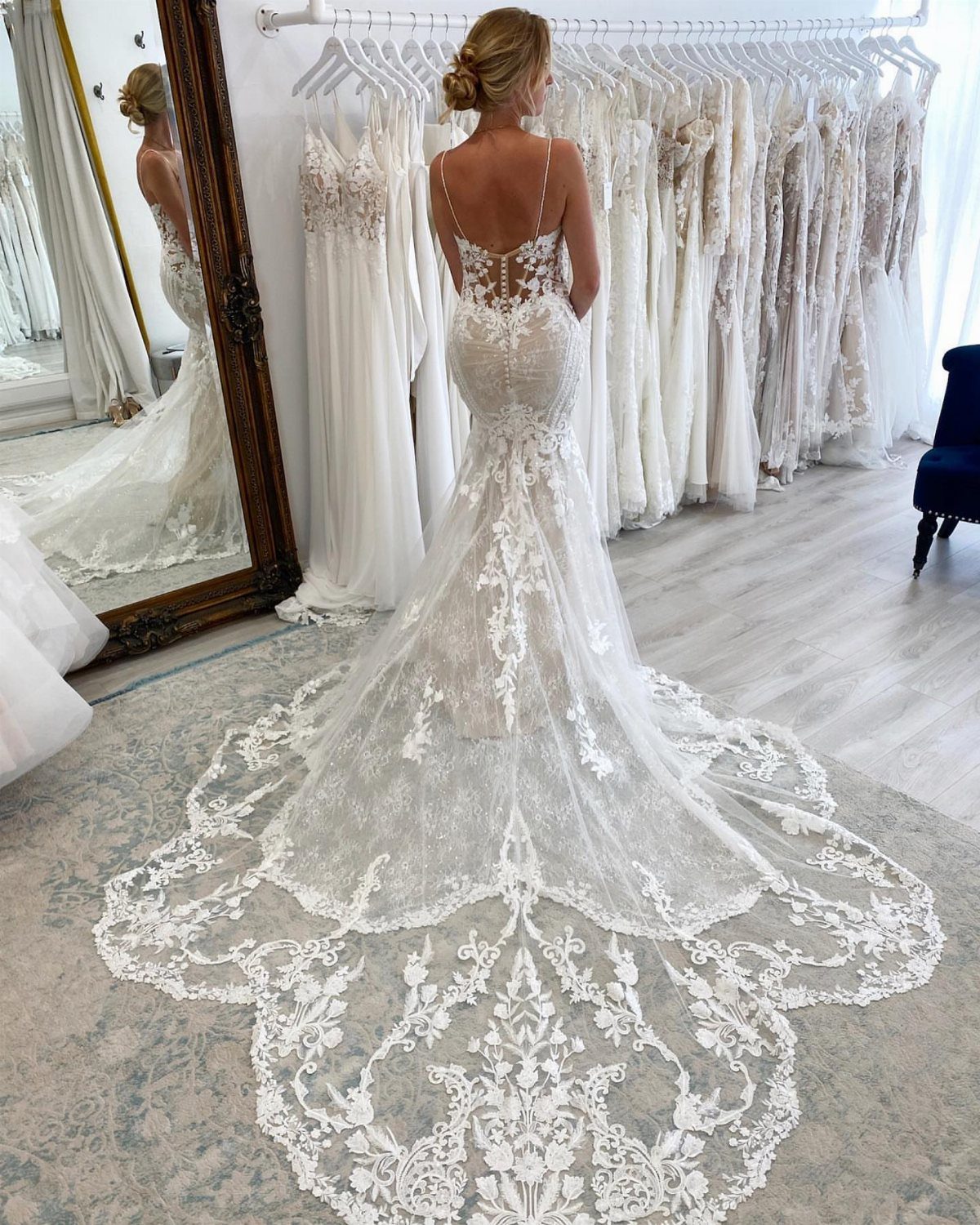 Woman wearing a white lace mermaid wedding dress with a long ornate train