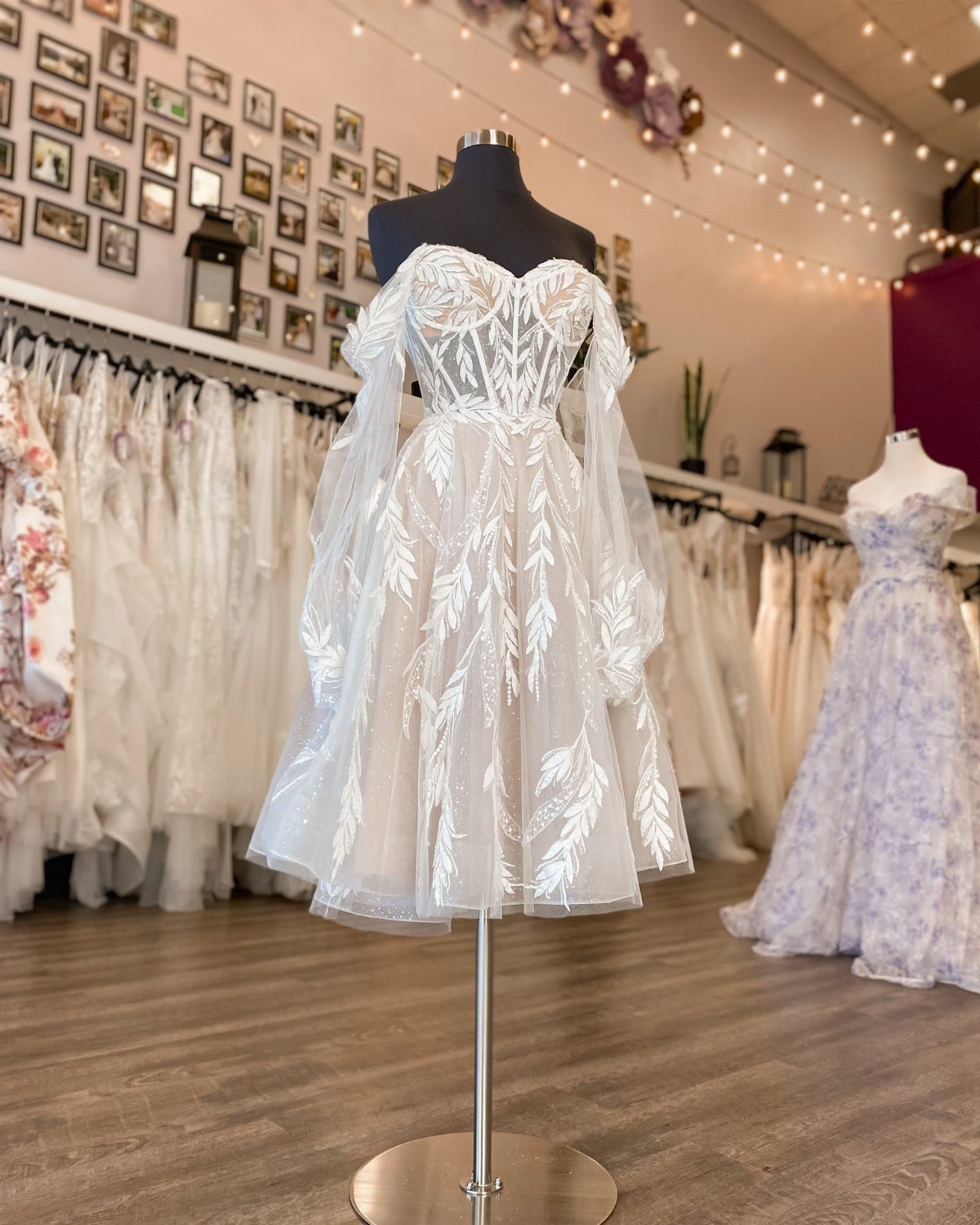 White knee-length wedding dress with lace leaf appliques on a bridal mannequin.