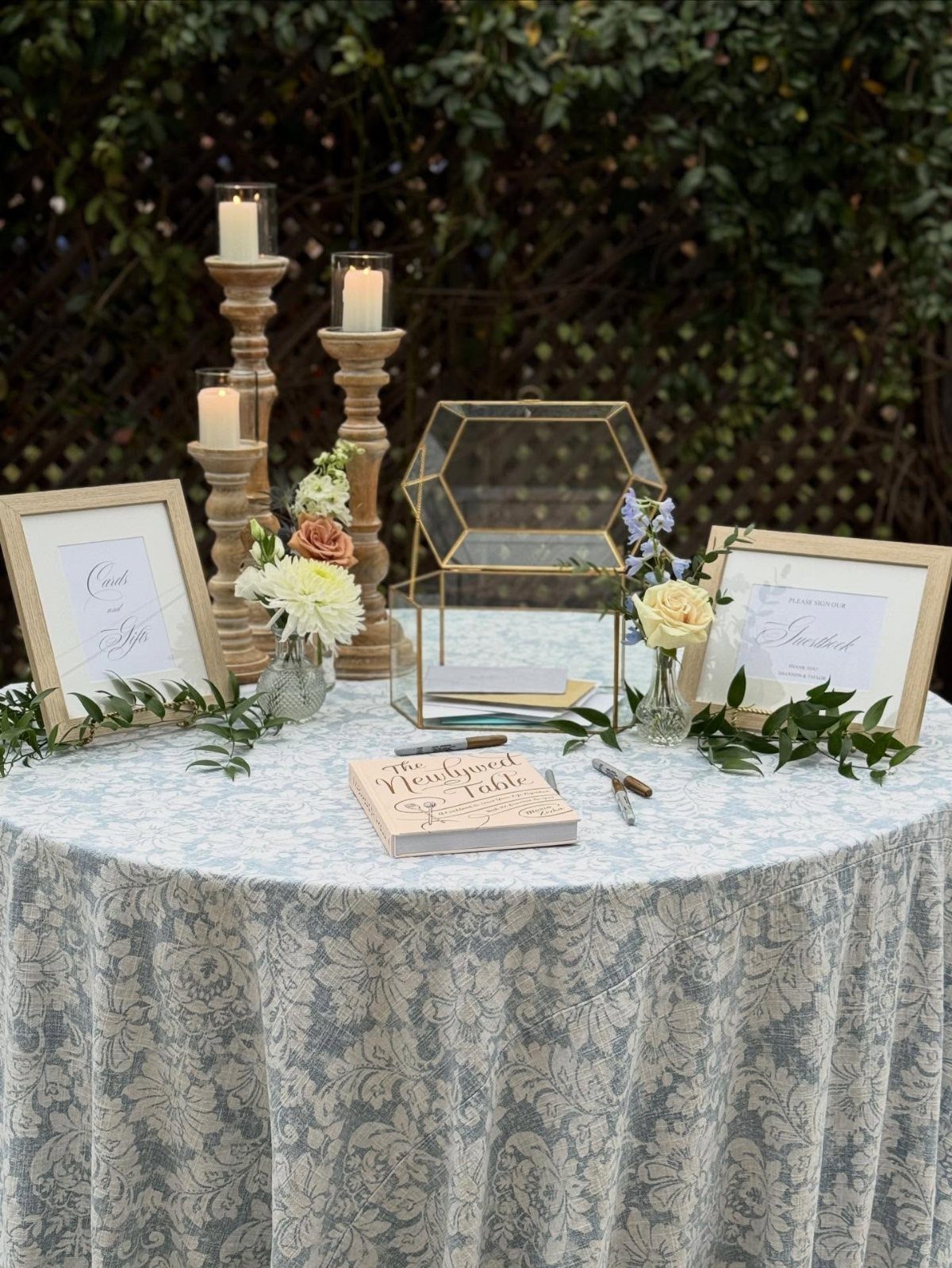 Wedding guest book table with blue damask cloth, candles, and gold accents.